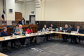 Secretary Scott is sitting at a table and addressing other participants.