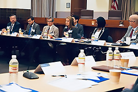 Secretary Hughs sitting at a table that surrounds the room with  the TBAT committee.