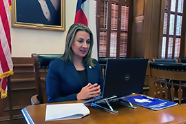 El secretaria Hughs sentado en un escritorio frente a una computadora.