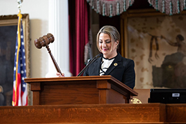 Secretary Hughs is holding a gavel is about to strike the top of the podium to commence session.