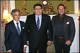 Texas Secretary of State Rolando Pablos standing in front of fireplace with two other officials. 
