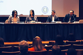 Four representatives sitting at a long table who are facing the audience. 